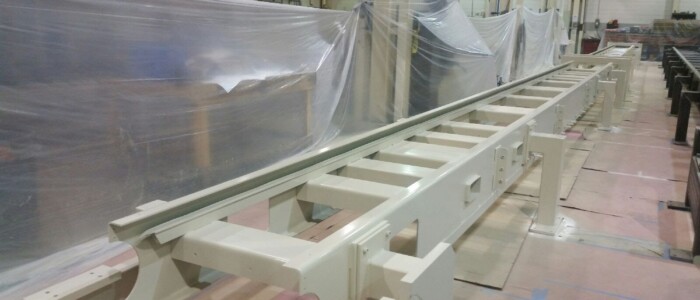 Freshly painted long conveyer machine equipment in a light beige color drying in a manufacturing area.