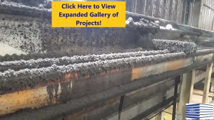 High-level piping in an industrial environment thickly coated with black dirt, dust, and manufacturing by-product with yellow box and blue text that says Click Here to View Expanded Gallery of Projects